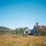 rustic timber house and church on blooming meadow in hilly countryside